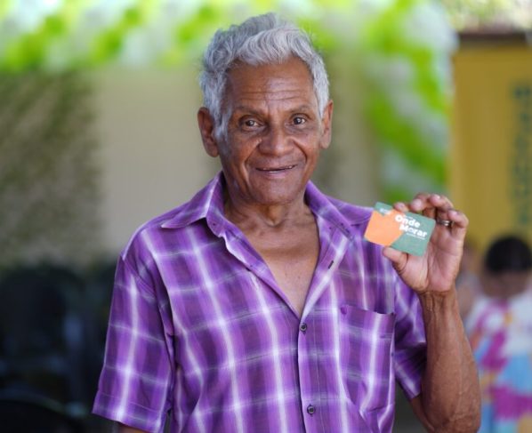 Famílias de Divinópolis são beneficiadas com Aluguel Social nesta segunda-feira - homem negro de aproximadamente 70 anos segurando cartão do Aluguel Social