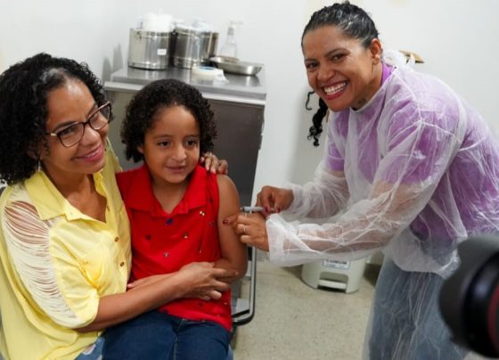 Goiânia e Aparecida antecipam ampliação da vacinação contra gripe - criança no colo da mãe recebendo vacina