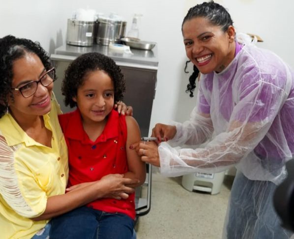 Goiânia e Aparecida antecipam ampliação da vacinação contra gripe - criança no colo da mãe recebendo vacina