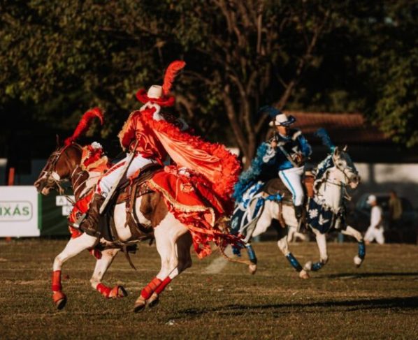 Cavalhadas de Crixás preservam tradição centenária em Goiás - encenação da batalha entre mouros e cristãos - cavaleiros em cavalos brancos e vestindo trajes nas cores azul e vermelha