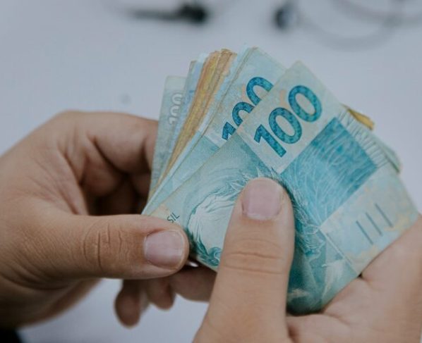 Nota Fiscal Goiana: começa prazo para resgate dos prêmios do sorteio de maio - notas de 50 e 100 reais na mão de uma pessoa