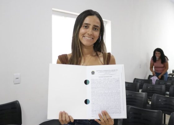 Governo de Goiás entrega 98 escrituras de casas a custo zero em Bom Jardim e Piranhas - Mulher jovem e de cabelos longos com escritura em mãos